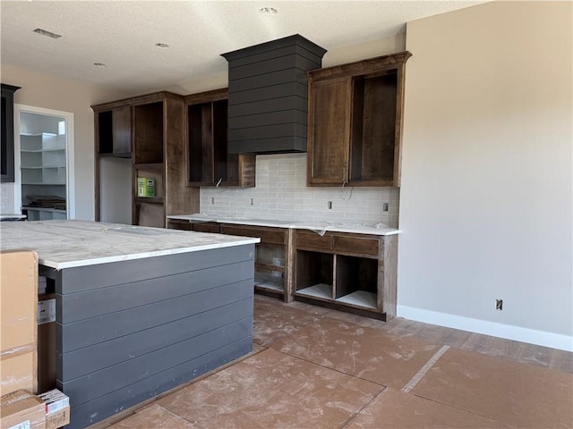 kitchen featuring baseboards, dark brown cabinetry, and decorative backsplash