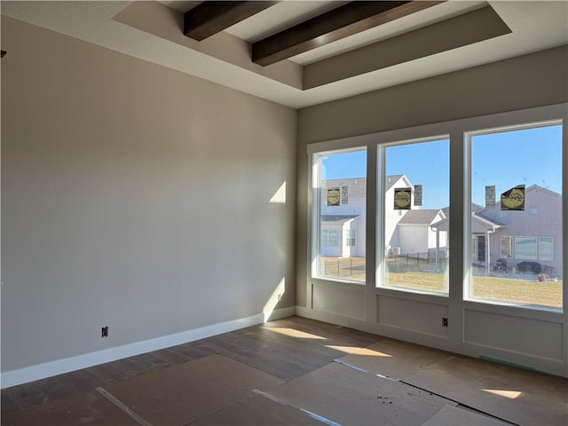 spare room featuring baseboards, beam ceiling, and wood finished floors