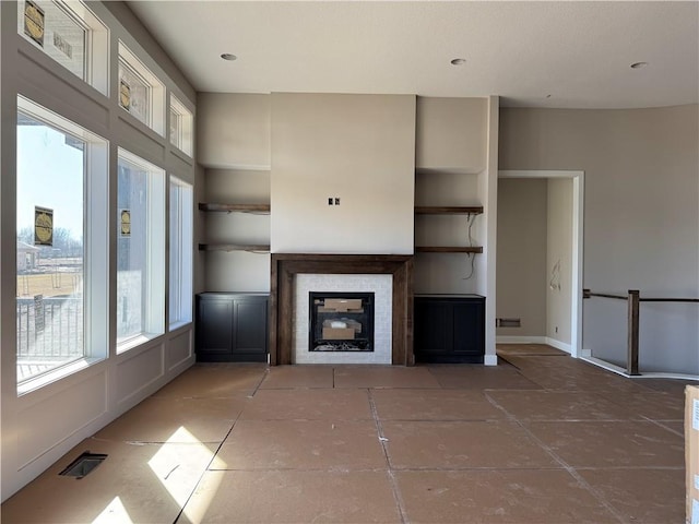 unfurnished living room featuring a glass covered fireplace, visible vents, and baseboards