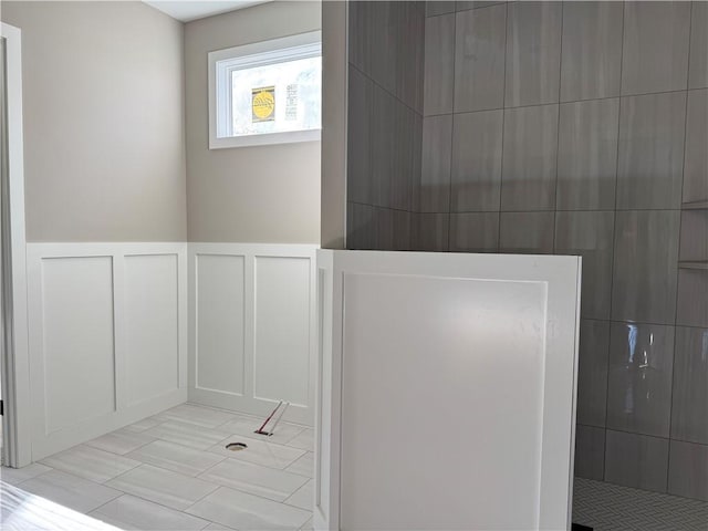 bathroom with wainscoting, a decorative wall, and walk in shower