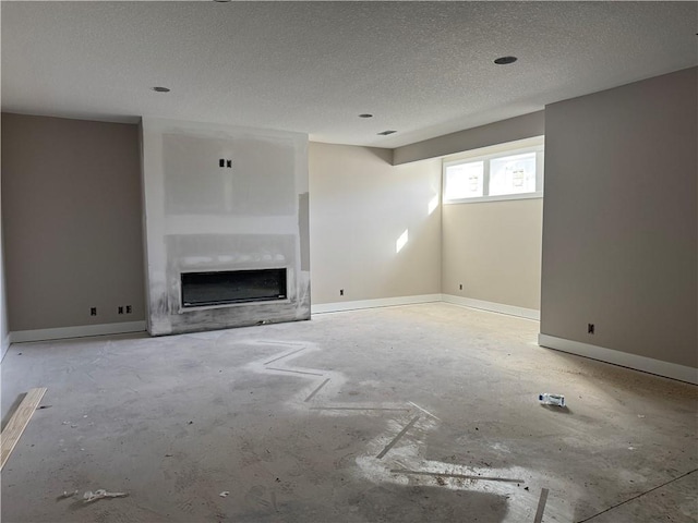 unfurnished living room with a textured ceiling, a fireplace, and baseboards