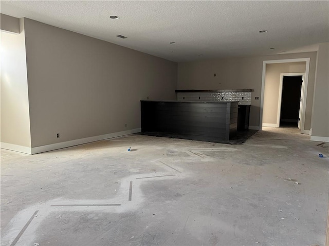 empty room with unfinished concrete flooring, a textured ceiling, and baseboards