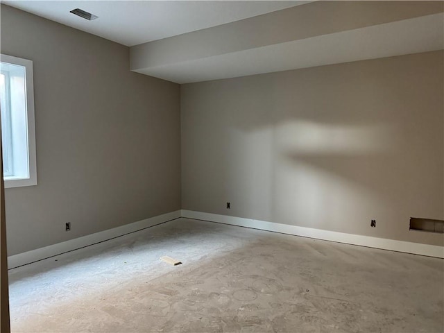 spare room with baseboards, visible vents, and unfinished concrete floors