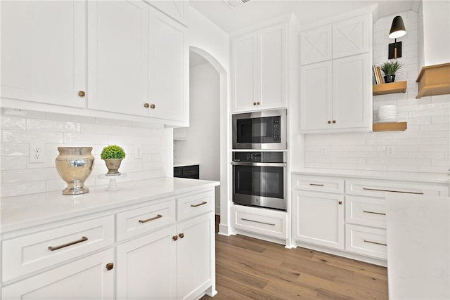 kitchen with light wood-type flooring, decorative backsplash, stainless steel appliances, and white cabinets