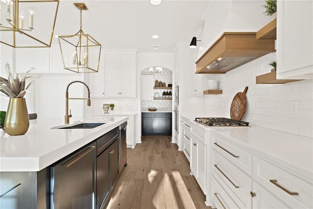 kitchen with white cabinets, sink, hanging light fixtures, and light hardwood / wood-style floors