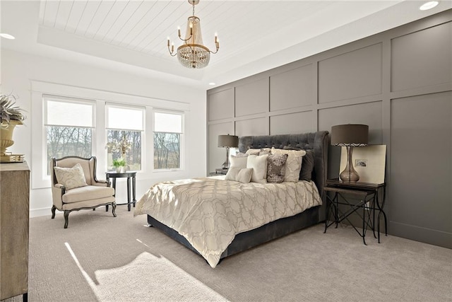 carpeted bedroom featuring a tray ceiling and a chandelier