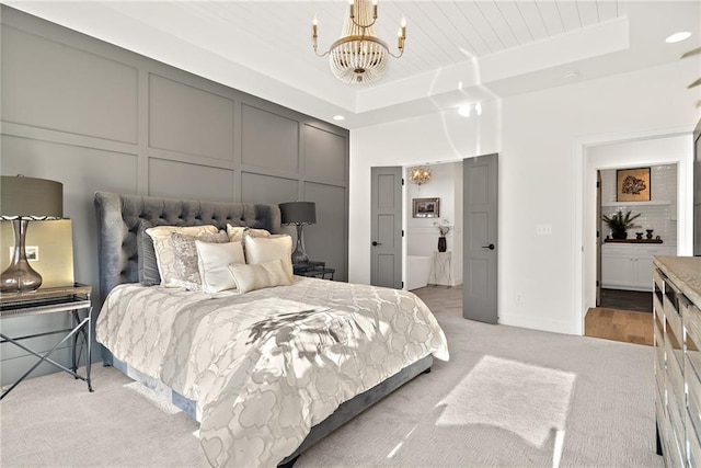 bedroom with an inviting chandelier, a raised ceiling, and light wood-type flooring