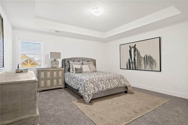 bedroom featuring a tray ceiling and dark colored carpet