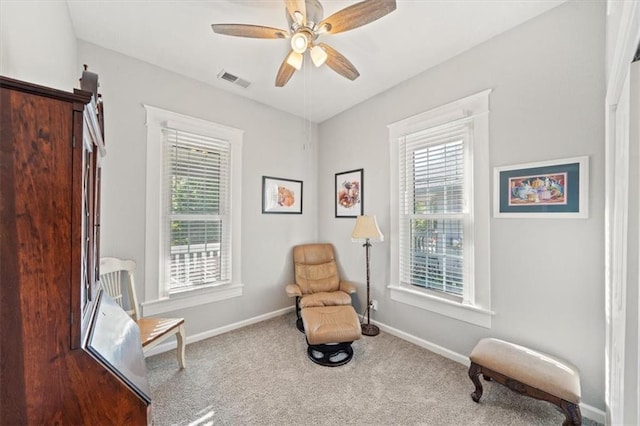 living area with carpet floors, ceiling fan, and plenty of natural light