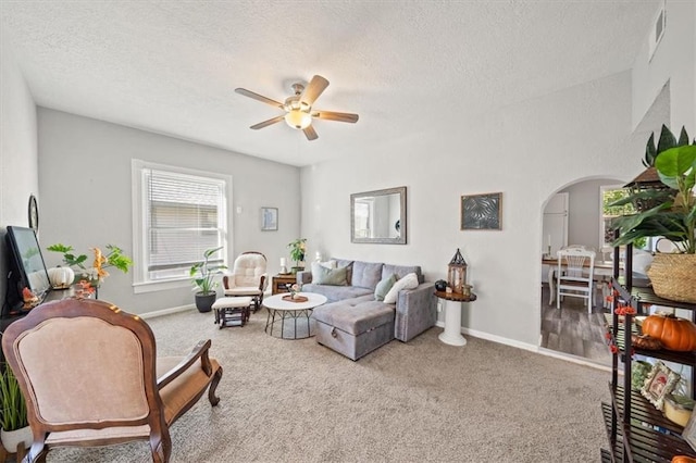 living room featuring ceiling fan, carpet floors, and a textured ceiling