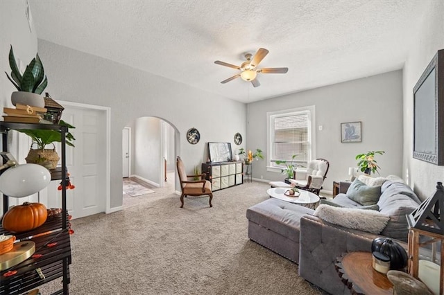 living room with light carpet, ceiling fan, and a textured ceiling