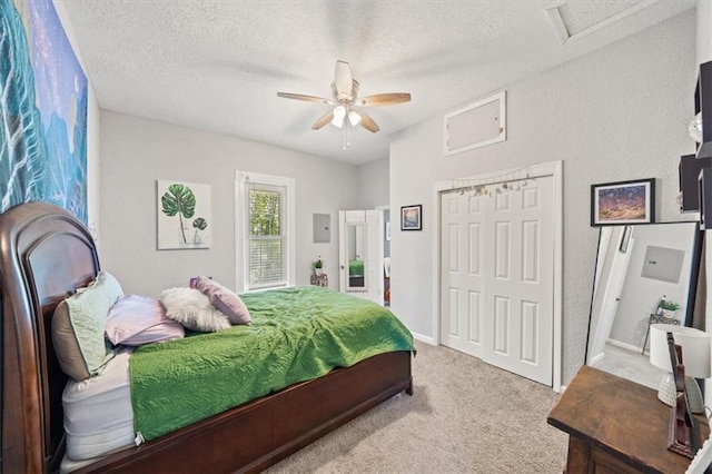 carpeted bedroom with a closet, ceiling fan, and a textured ceiling