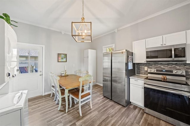 kitchen with white cabinets, hanging light fixtures, appliances with stainless steel finishes, an inviting chandelier, and light hardwood / wood-style floors