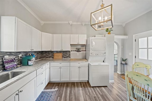 kitchen featuring stacked washer and clothes dryer, decorative light fixtures, white cabinetry, an inviting chandelier, and light wood-type flooring