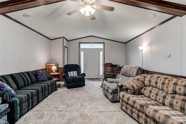 carpeted living area featuring ornamental molding, vaulted ceiling with beams, and a ceiling fan