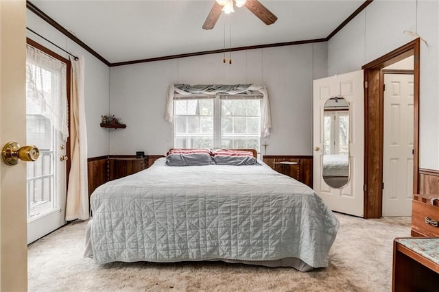 bedroom with multiple windows, light colored carpet, ornamental molding, and wainscoting