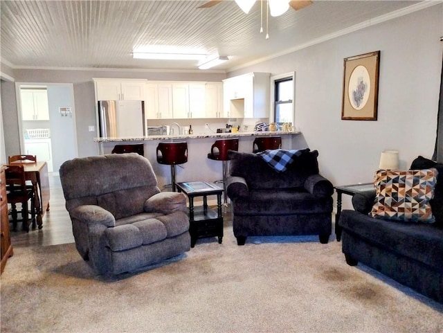 carpeted living room with ceiling fan and ornamental molding