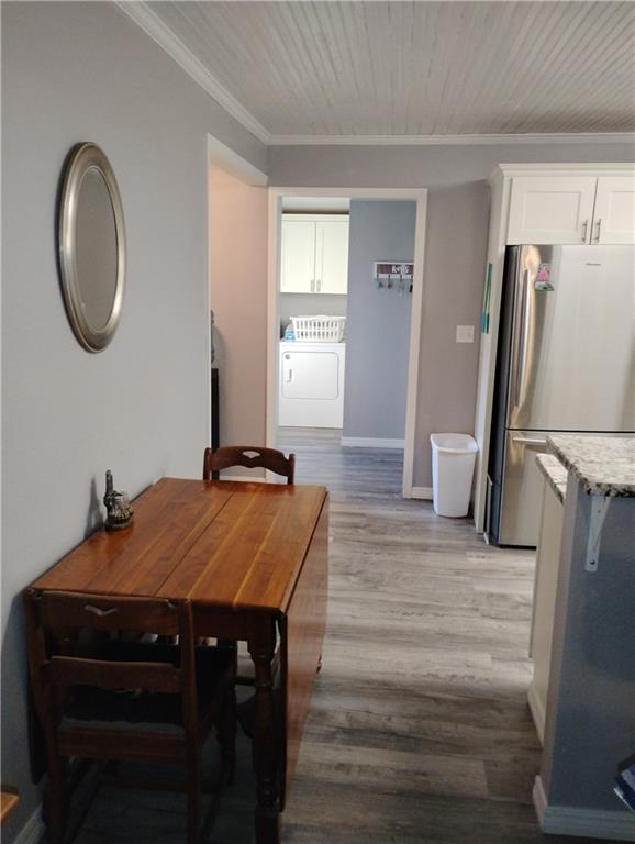 dining space with washer / dryer, ornamental molding, and light wood-type flooring