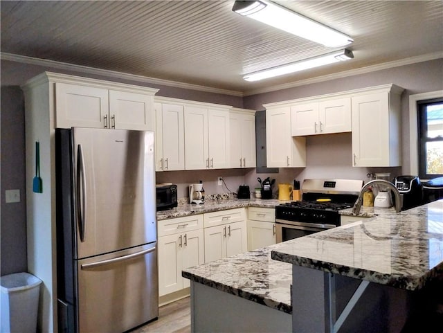 kitchen featuring appliances with stainless steel finishes, light stone counters, and white cabinetry