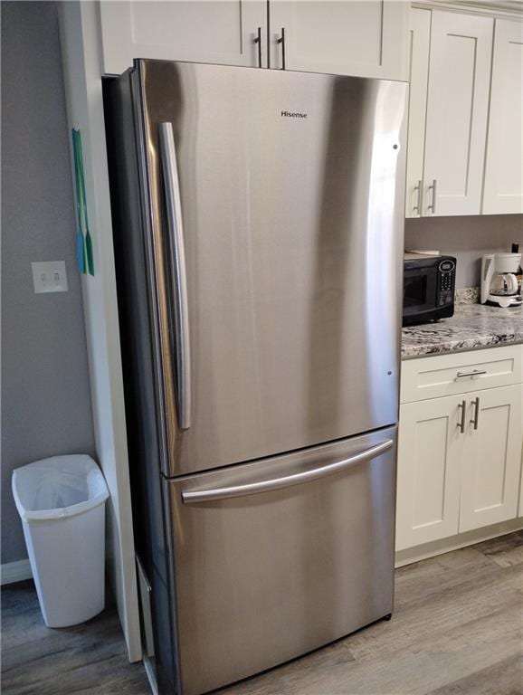 kitchen featuring white cabinetry, light hardwood / wood-style flooring, and stainless steel refrigerator