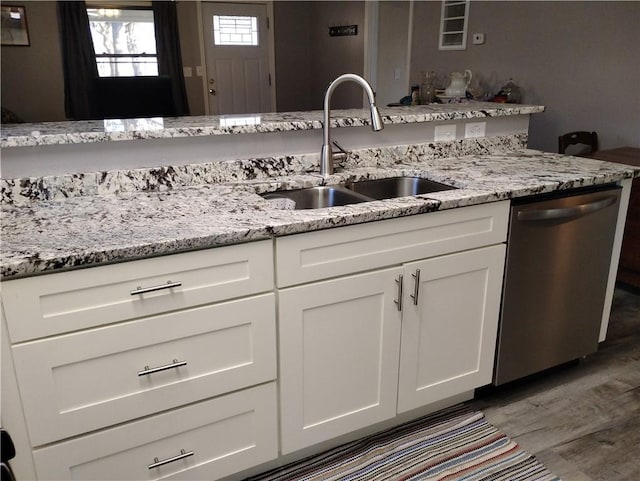 kitchen featuring white cabinetry, dishwasher, light stone counters, and sink