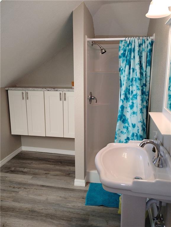 bathroom with walk in shower, lofted ceiling, sink, and hardwood / wood-style flooring