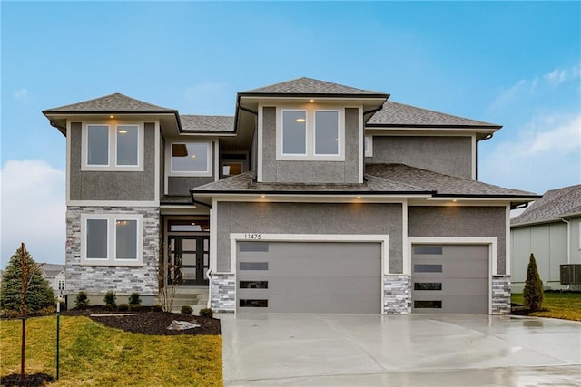 prairie-style home featuring cooling unit, a front yard, and a garage