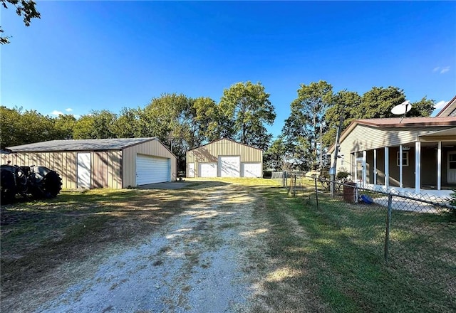 view of yard with an outdoor structure, fence, a garage, and driveway