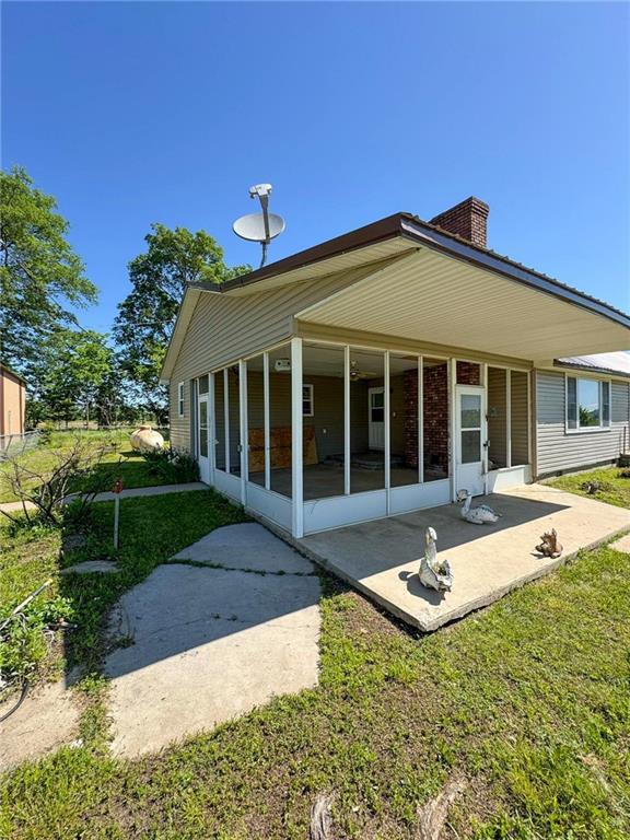 10784 SW 70th St, Chetopa, KS 67336 - back of house featuring a sunroom, a patio area, a yard, and a chimney