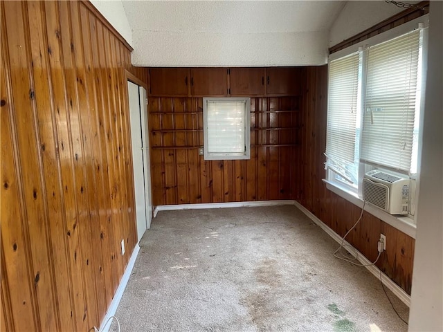 carpeted spare room featuring cooling unit and wooden walls