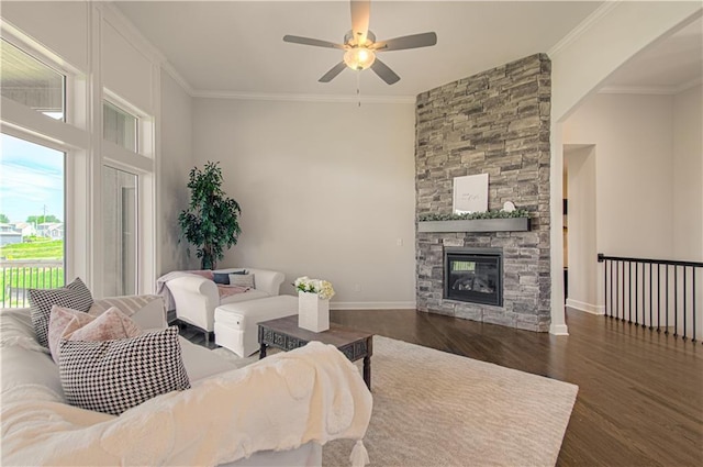 living area featuring a stone fireplace, ornamental molding, and wood finished floors