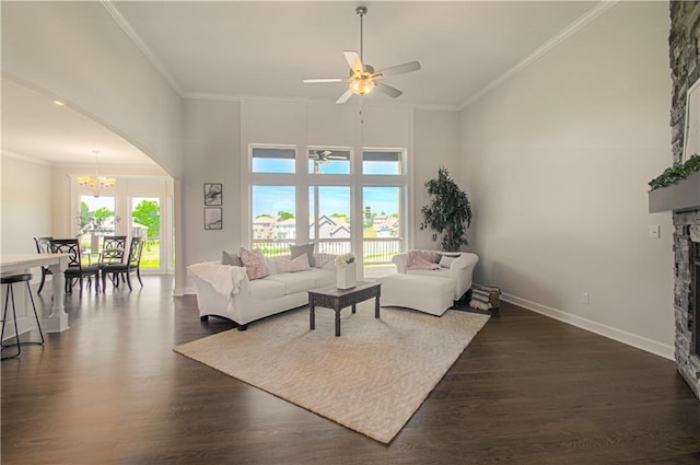 living area featuring a stone fireplace, dark wood-type flooring, a towering ceiling, and crown molding