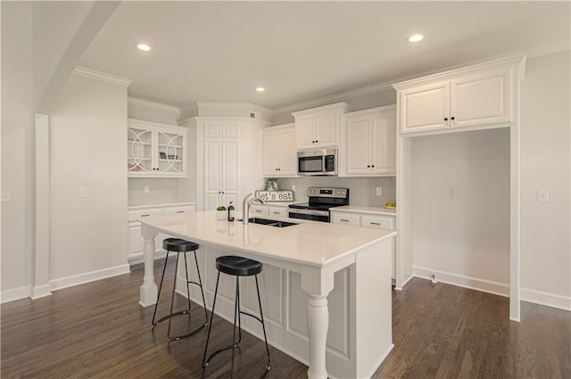 kitchen featuring arched walkways, a breakfast bar, appliances with stainless steel finishes, white cabinetry, and a sink