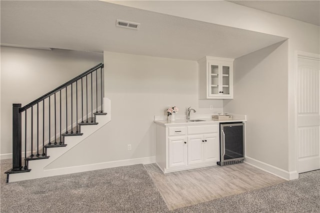 bar with visible vents, wine cooler, stairs, wet bar, and a sink