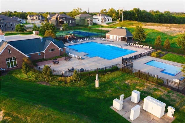 community pool featuring a yard, a patio area, fence, and a residential view