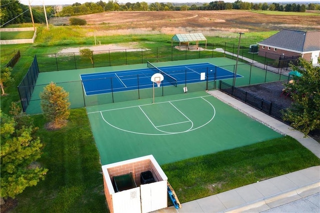 view of basketball court featuring a tennis court, community basketball court, fence, and a rural view