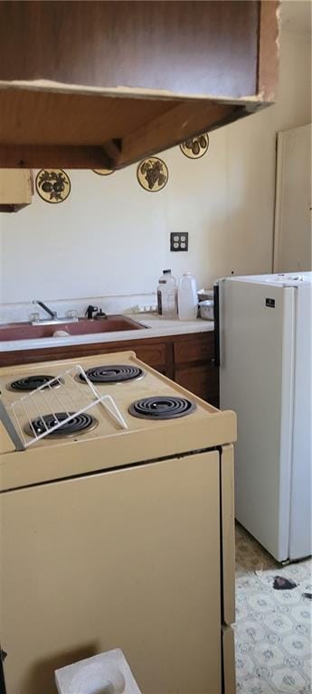 kitchen with range hood, white appliances, and sink