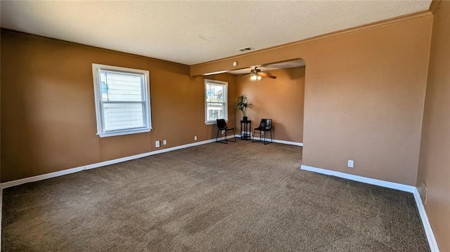 empty room with a textured ceiling, carpet flooring, ornamental molding, and ceiling fan