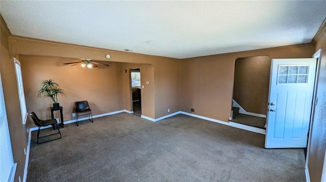 spare room featuring ceiling fan, ornamental molding, a textured ceiling, and dark colored carpet