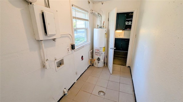 clothes washing area featuring washer hookup, gas water heater, electric panel, and light tile patterned flooring