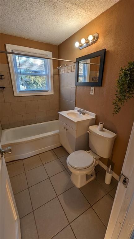 full bathroom with tile patterned flooring, a textured ceiling, vanity, tiled shower / bath, and toilet