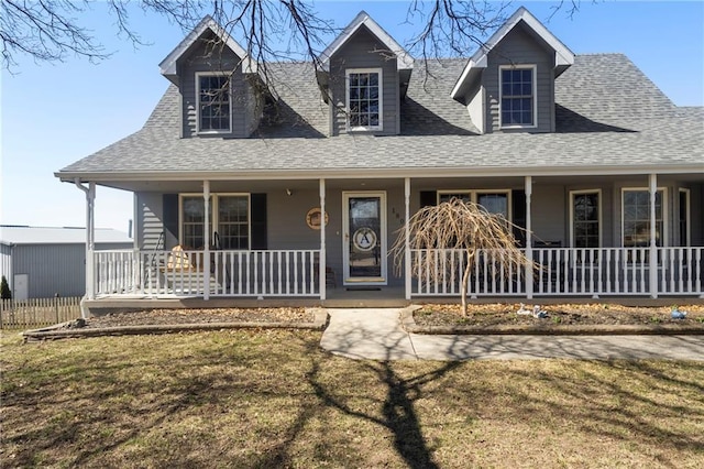 view of front of home with roof with shingles, a porch, and a front lawn