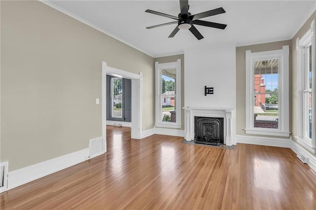 unfurnished living room featuring ornamental molding, ceiling fan, hardwood / wood-style flooring, and plenty of natural light