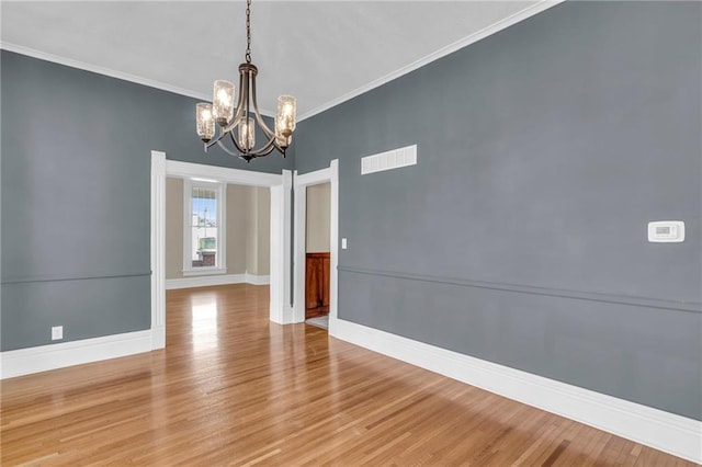 empty room with ornamental molding, an inviting chandelier, and hardwood / wood-style floors