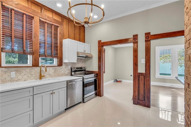 kitchen with pendant lighting, appliances with stainless steel finishes, a chandelier, and a healthy amount of sunlight