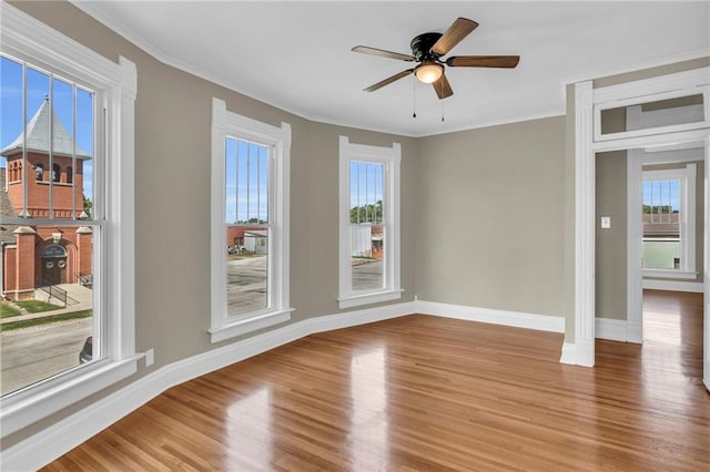 unfurnished room with a wealth of natural light, light hardwood / wood-style floors, ceiling fan, and crown molding