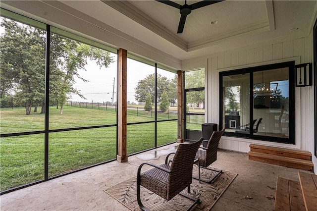 unfurnished sunroom featuring a tray ceiling and ceiling fan