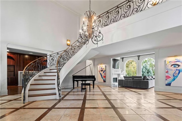 foyer entrance featuring a towering ceiling, decorative columns, and an inviting chandelier