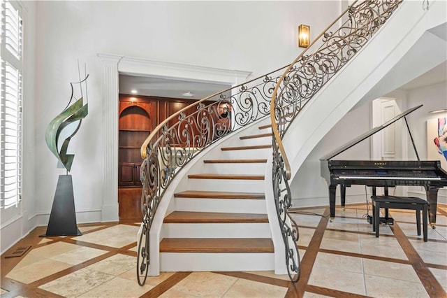 stairway featuring ornate columns, plenty of natural light, and tile patterned flooring