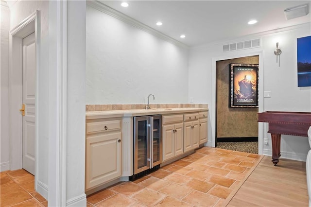 bar with light hardwood / wood-style flooring, beverage cooler, ornamental molding, and sink